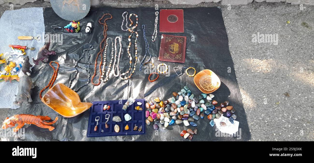 Mercato dell'antiquariato europeo, stand al mercato delle pulci: Pietre umili di cristallo colorate, gioielli di cristallo, collane color ambra, giocattoli vintage, libri vintage, perline di rosario vintage , collane in pietra naturale e minerali, ciondoli in pietra preziosa, bigiotteria vintage, pietra vintage ( pietre minerali pietre semi preziose ) bracciali in cristallo, fossili, agata, pietre umili al quarzo rosa, giocattoli di maiale vintage, giocattolo T-rex vintage, copertine di libri vintage in pelle, acquette in bronzo, ciotola in legno intagliato a mano, mercato delle pulci estive, giocattolo hipo Foto Stock