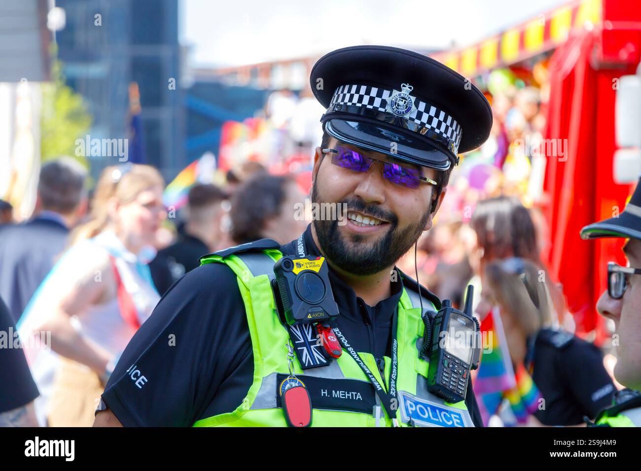 Agente di polizia asiatico con occhiali da sole e barba sorridente al Birmingham Pride che celebra la diversità e l'uguaglianza LGBT+ Foto Stock