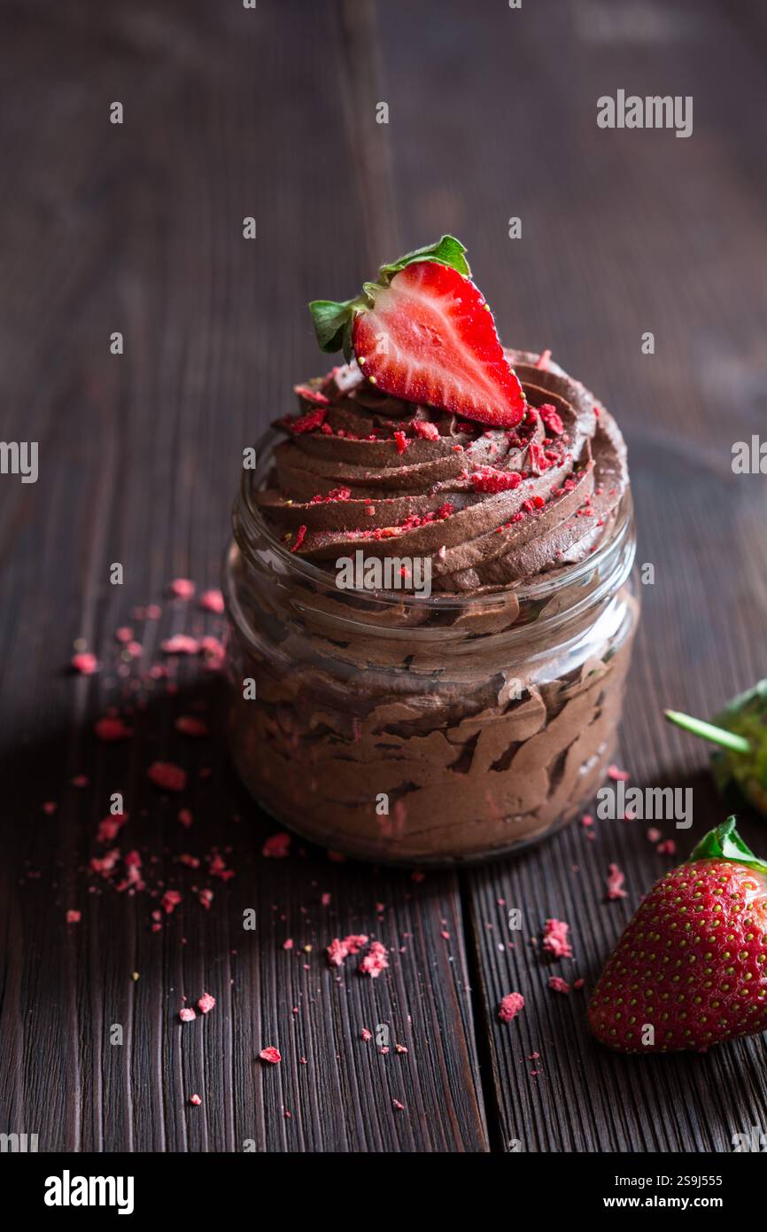 Deliziosa mousse al cioccolato ricoperta di fragole fresche e liofilizzate in vasetti di vetro Foto Stock
