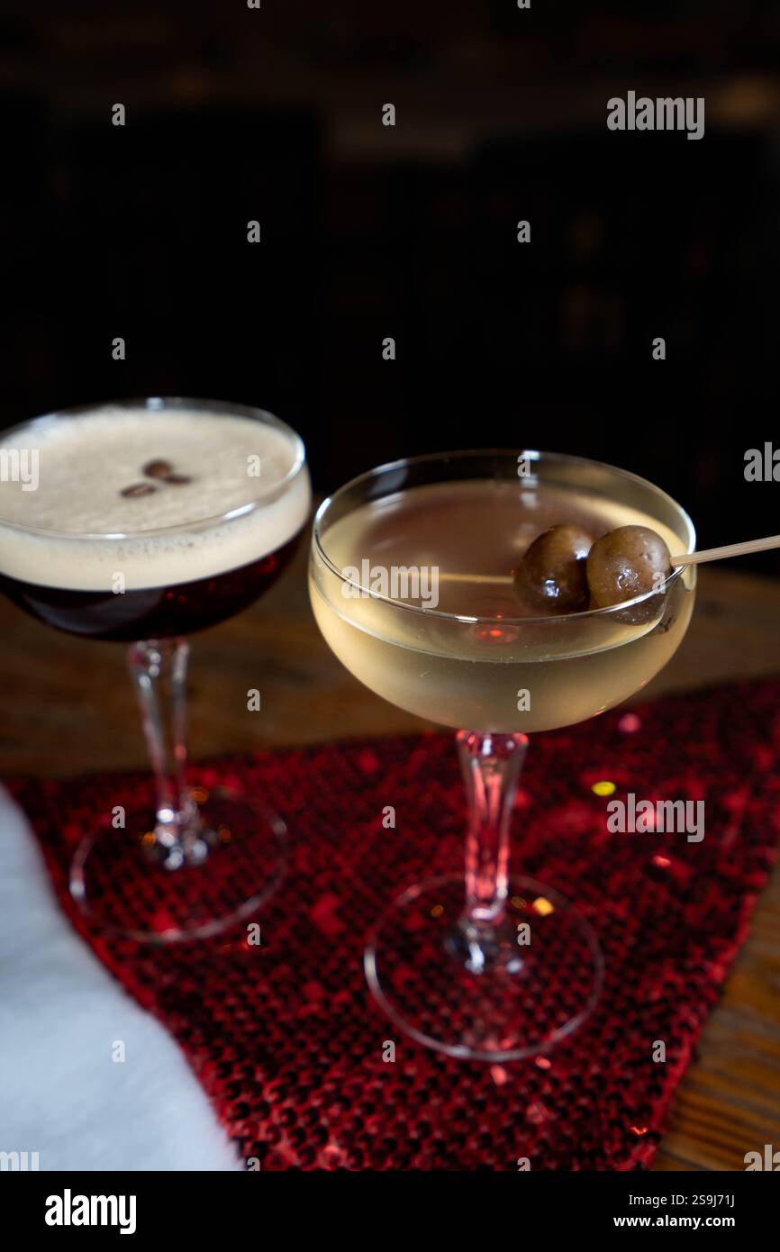 La foto mostra un martini sporco e un espresso martini posto su un cappello di Babbo Natale rosso scintillante. L'allestimento natalizio combina il divertimento delle vacanze con l'eleganza Foto Stock