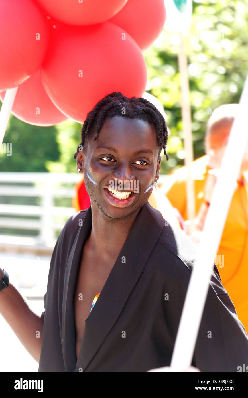 Sorridente giovane nero con palloncini rossi al Birmingham gay Pride che celebra la diversità e l'uguaglianza LGBT+ Foto Stock