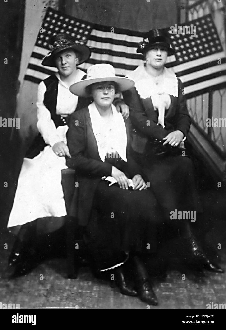 Tre donne posano di fronte a una bandiera americana, circa 1915. Foto Stock