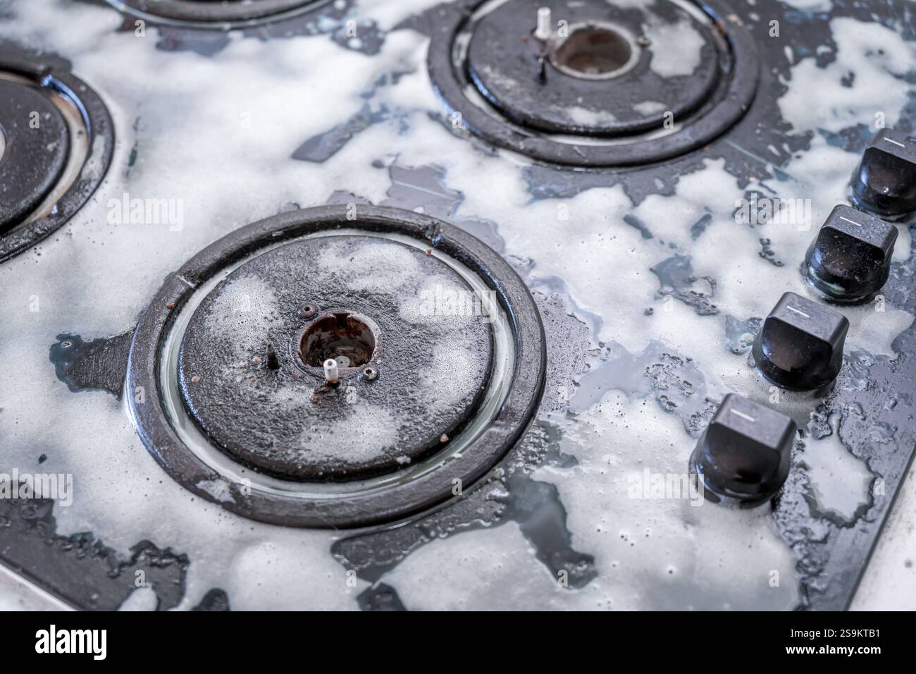 Pulizia di una stufa a gas con utensili da cucina, concetti domestici, o igiene e pulizia Foto Stock