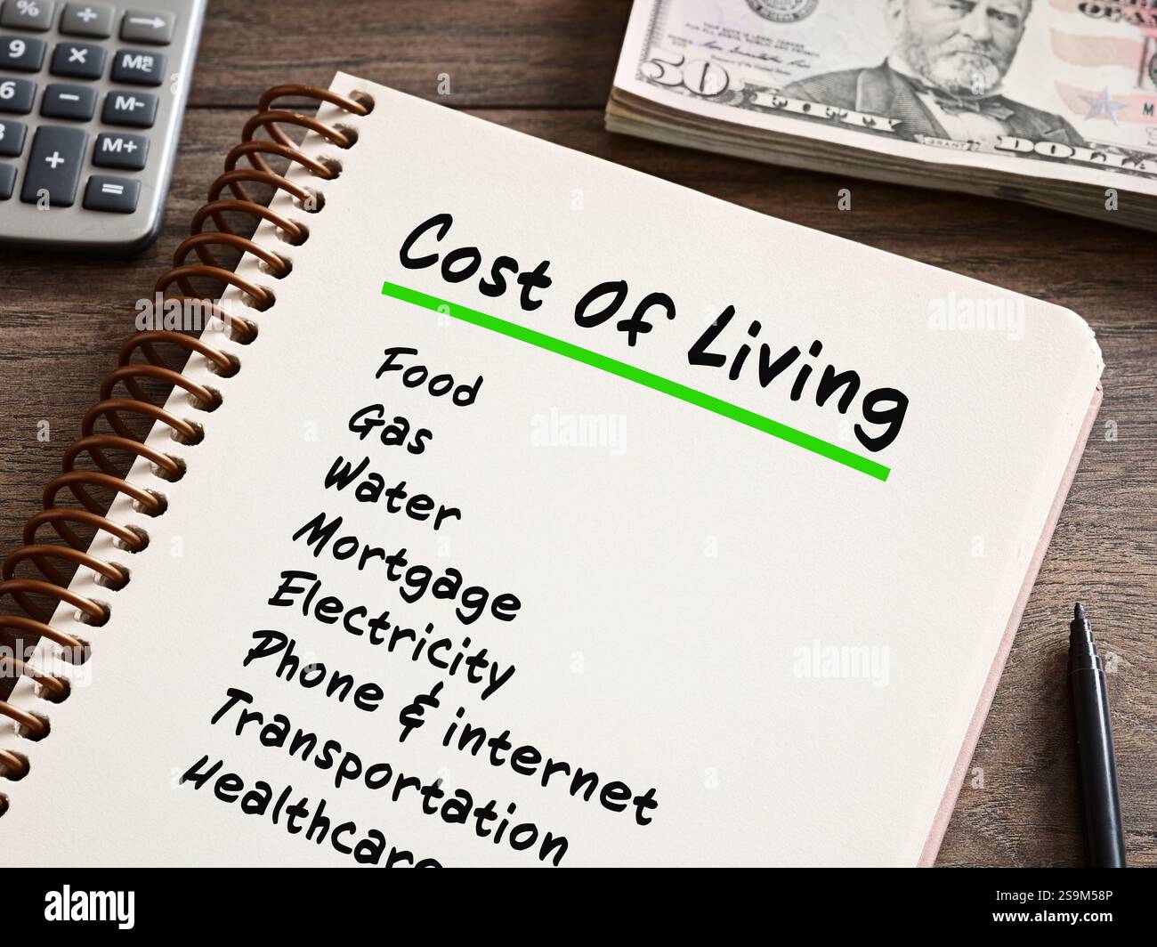 Notebook che elenca il costo delle spese di vita con calcolatrice e banconote in dollari USA, concetto di inflazione e aumento dei prezzi Foto Stock