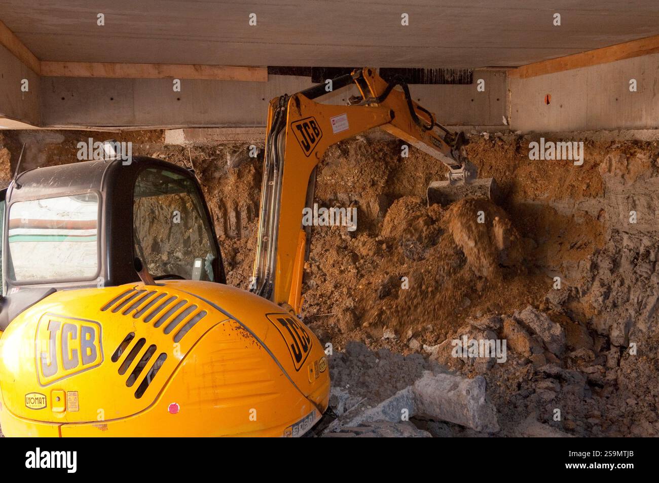 Scavo di un parcheggio sotterraneo, con mini attrezzature di movimento terra. Foto Stock