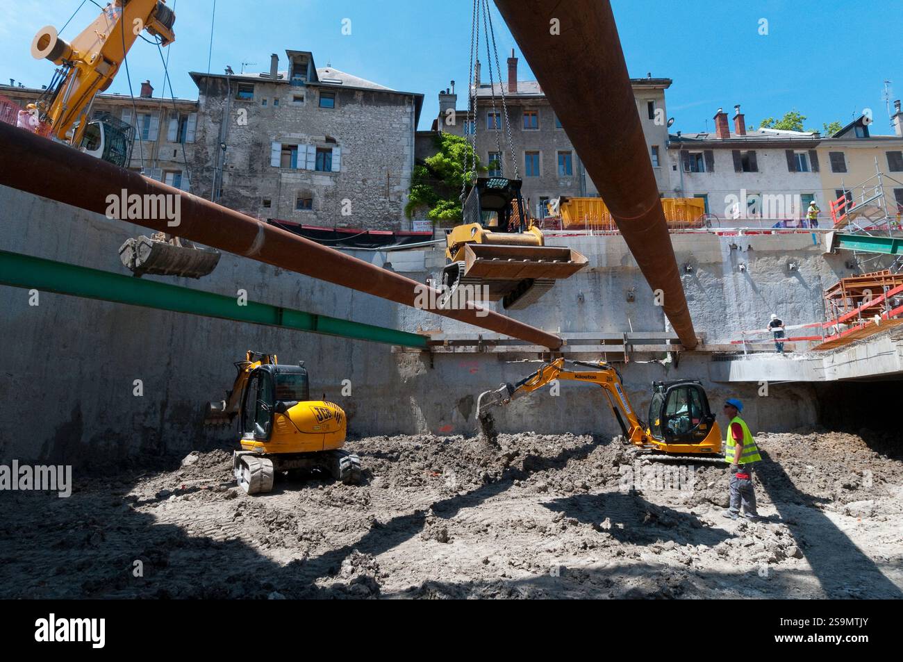 Scavo di un parcheggio sotterraneo in città, con mini attrezzature di movimento terra. Con le mura. Foto Stock