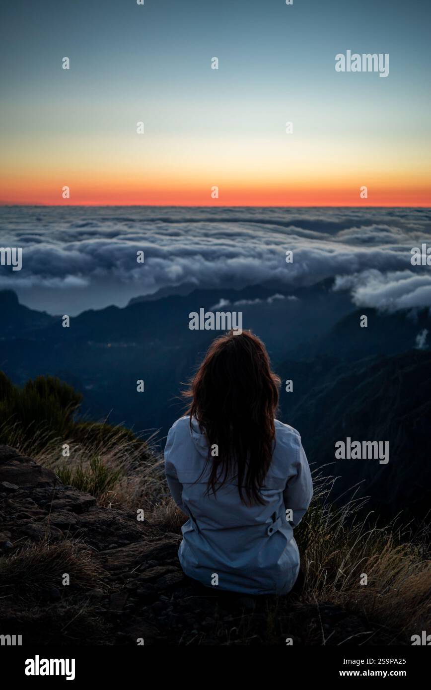 Viaggiatore che guarda l'alba sopra le nuvole Foto Stock