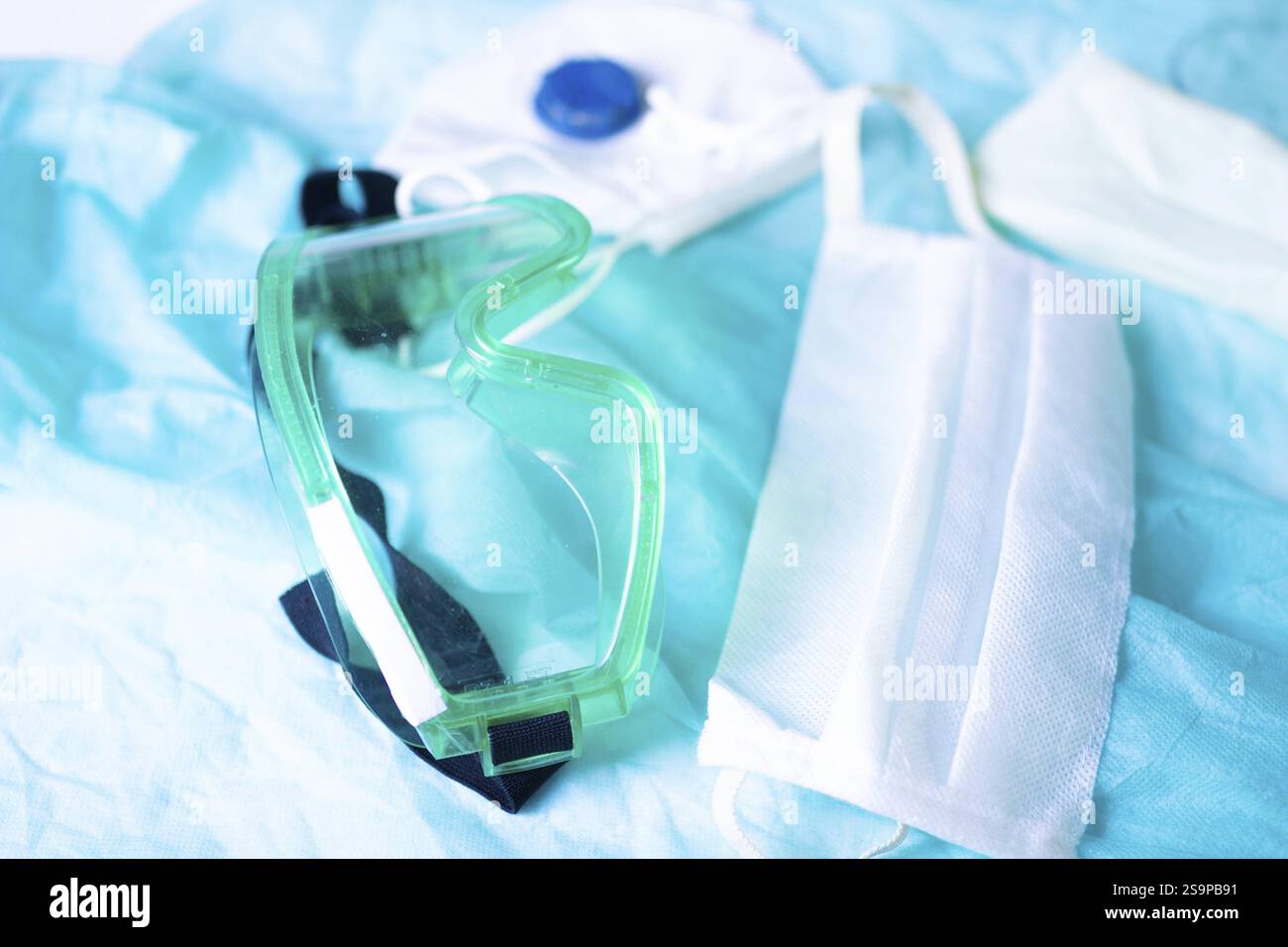 Equipaggiamento di sicurezza con occhiali, maschera e guanti su un panno color acqua Foto Stock