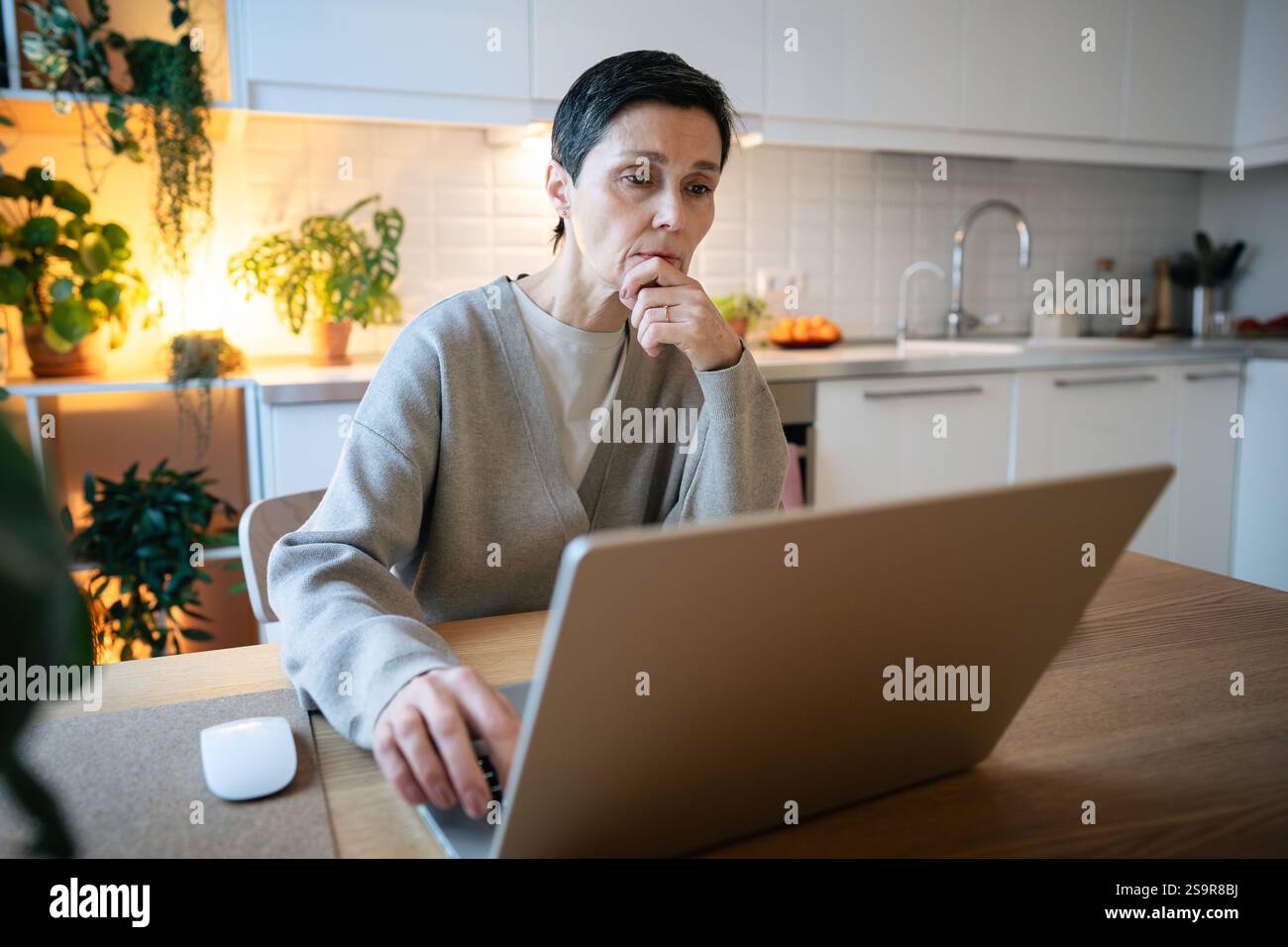 Donne attente che usano un notebook in cucina e cercano soluzioni. Bilanciare le scadenze, lavorare in remoto Foto Stock