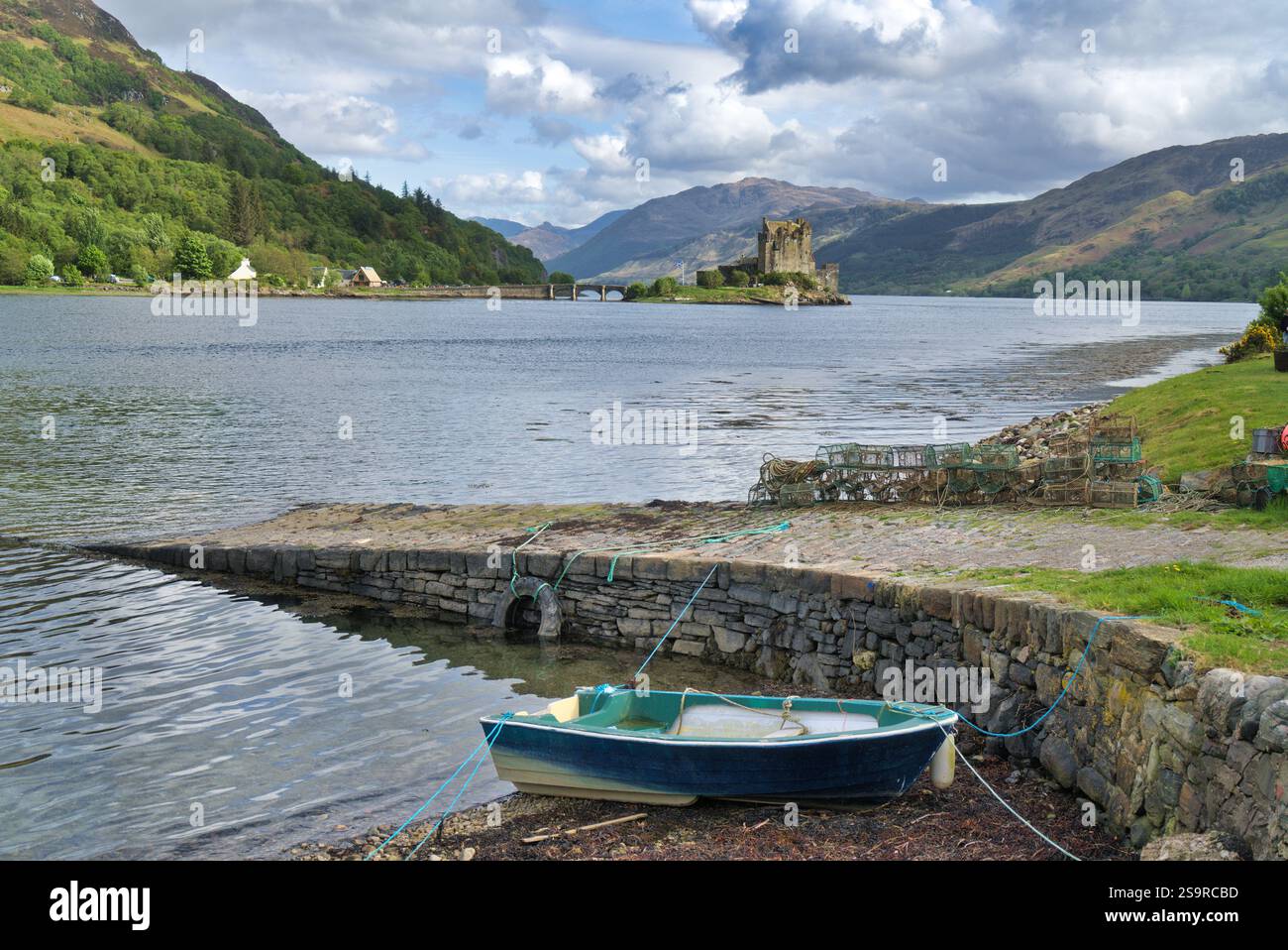 Guardando verso sud lungo Loch Duich fino al castello di Eilean Donan, accanto alla strada principale A87 per Skye. Barca sullo scalo. Morvich, Highlands occidentali, Scozia, Regno Unito Foto Stock