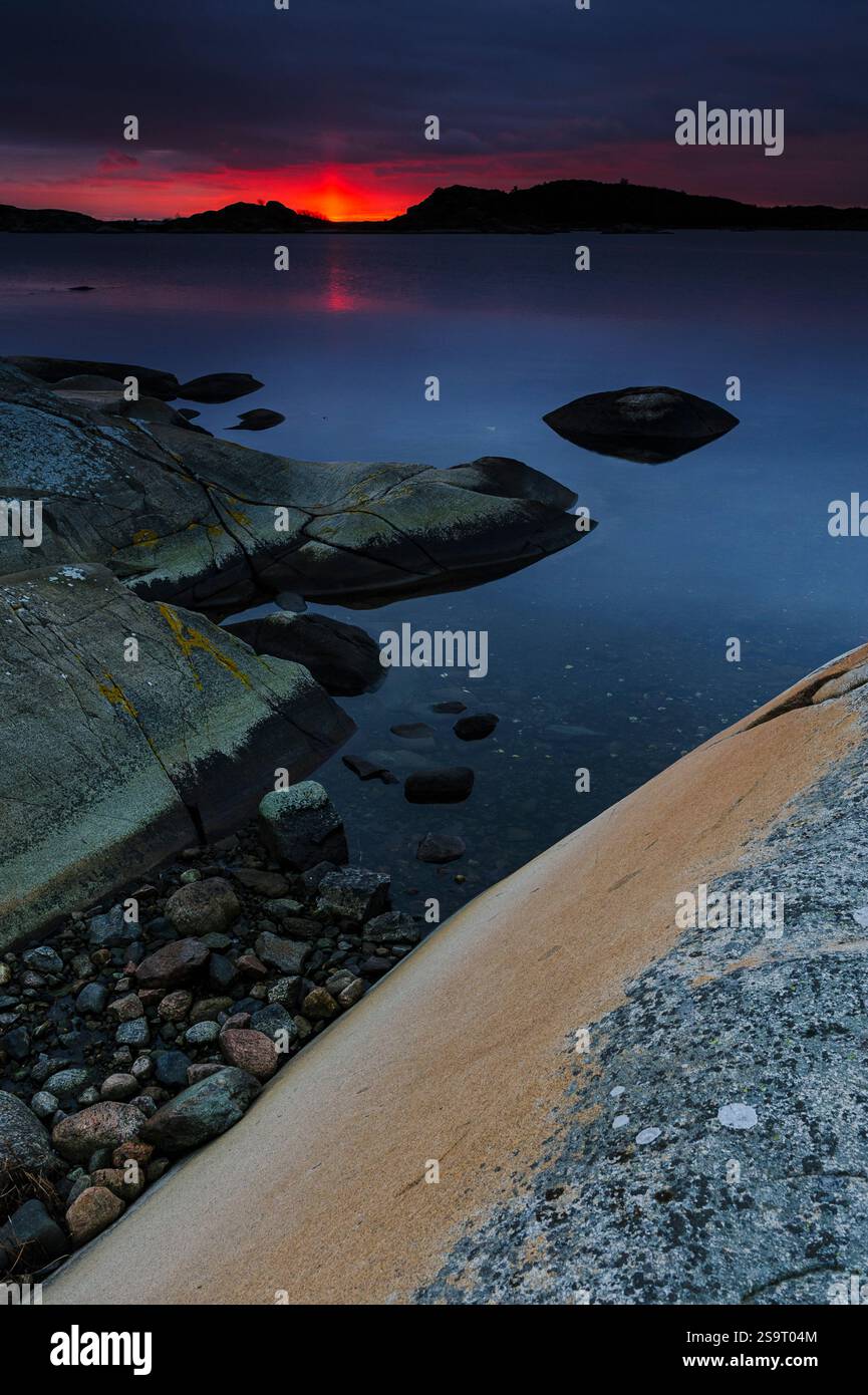 Splendido paesaggio costiero vicino a Goteborg al tramonto, dove i colori vivaci si fondono nel cielo, riflettendo sulle acque calme. Le coste rocciose portano al Foto Stock