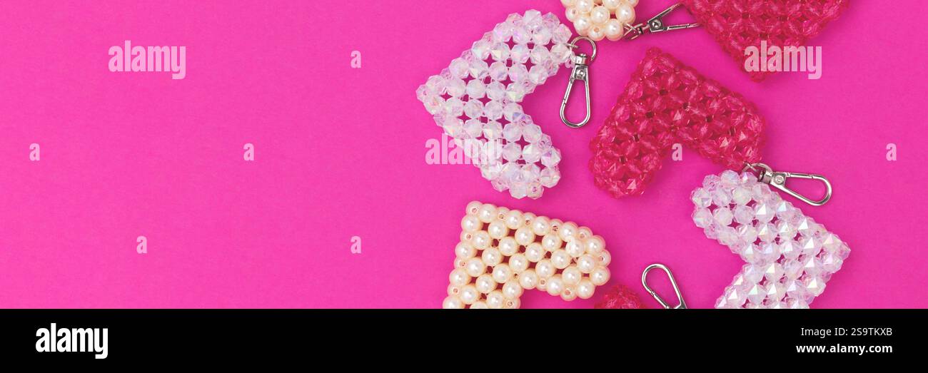 Striscione con portachiavi a forma di cuore realizzato con perline su sfondo magenta. Foto Stock