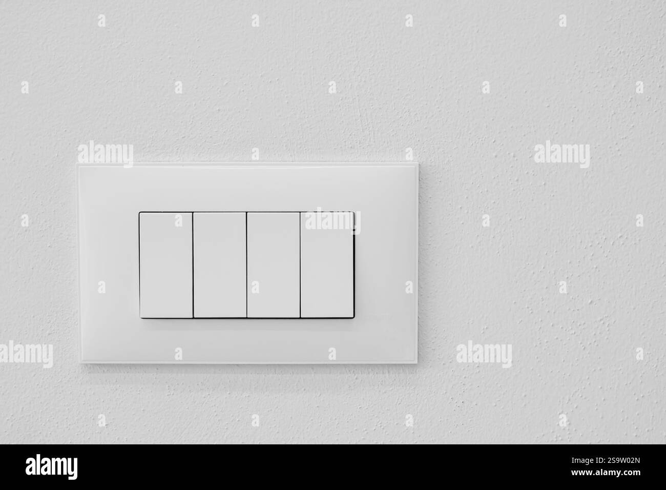 Primo piano di un moderno interruttore luci europeo. Quattro grandi interruttori di accensione e spegnimento su pareti in cemento. Interruttore luminoso su una parete bianca nell'appartamento. Foto Stock