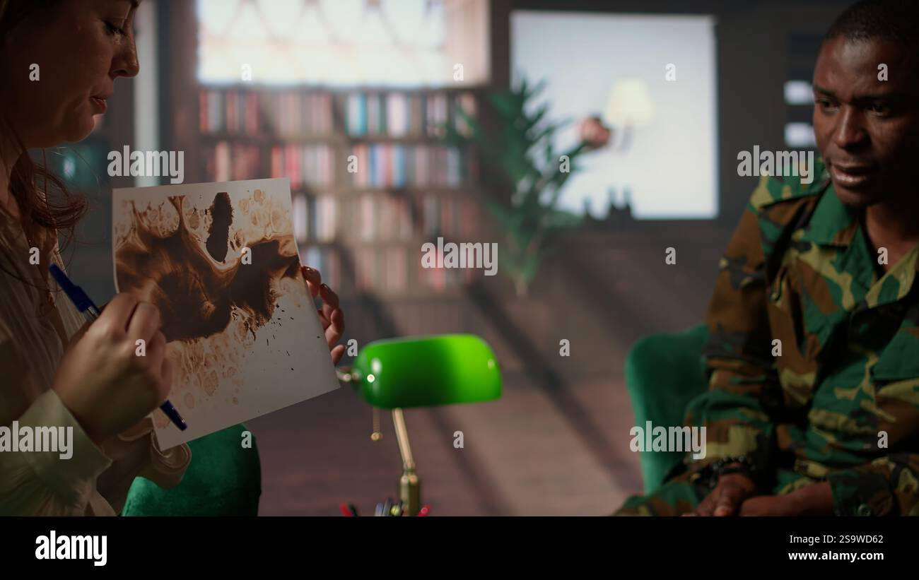 Il veterano militare studia il lotto di inchiostro di Rorschach in sessione di terapia con il consulente, affrontando i problemi di PTSD e recupero da trauma. La donna mostra sostegno psicologico per l'assistenza alla salute mentale. Telecamera A.. Foto Stock