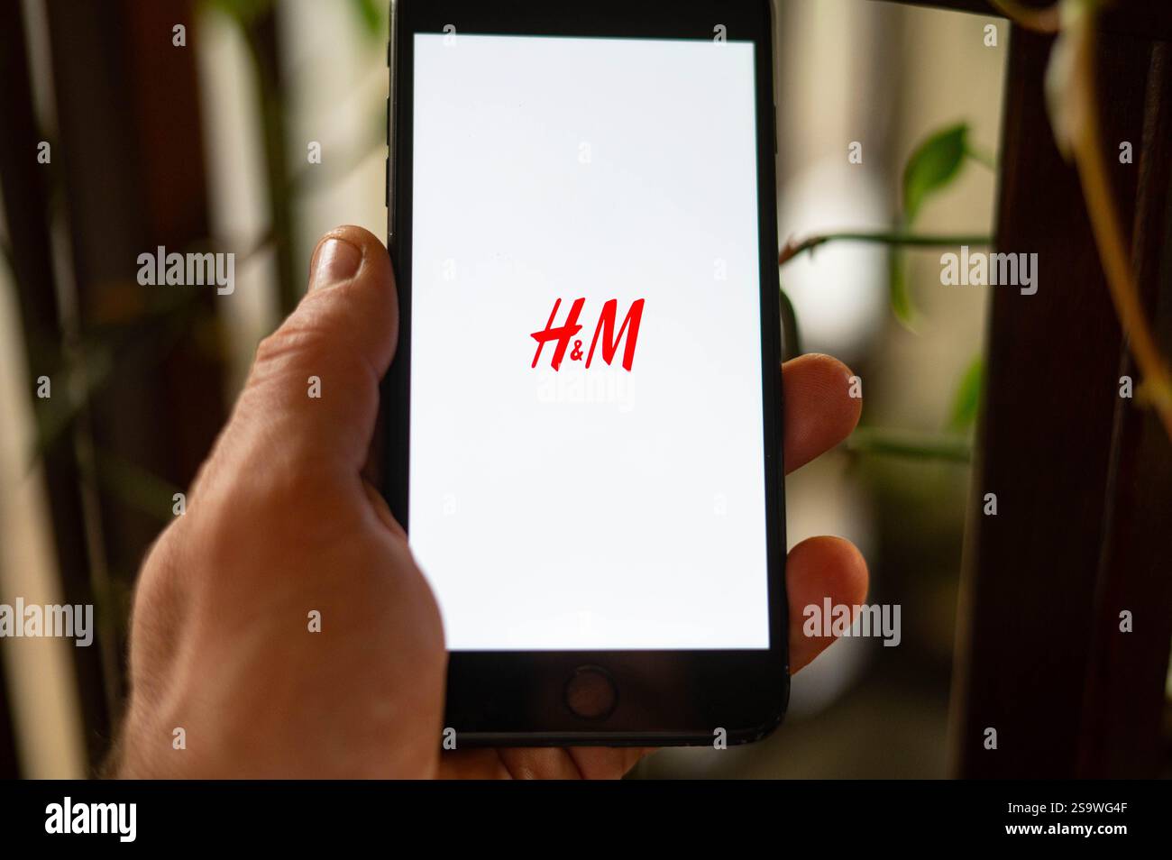 Una persona sta aprendo l'app H&M Storet su un telefono. H&M è una multinazionale svedese di abbigliamento al dettaglio. Foto Stock