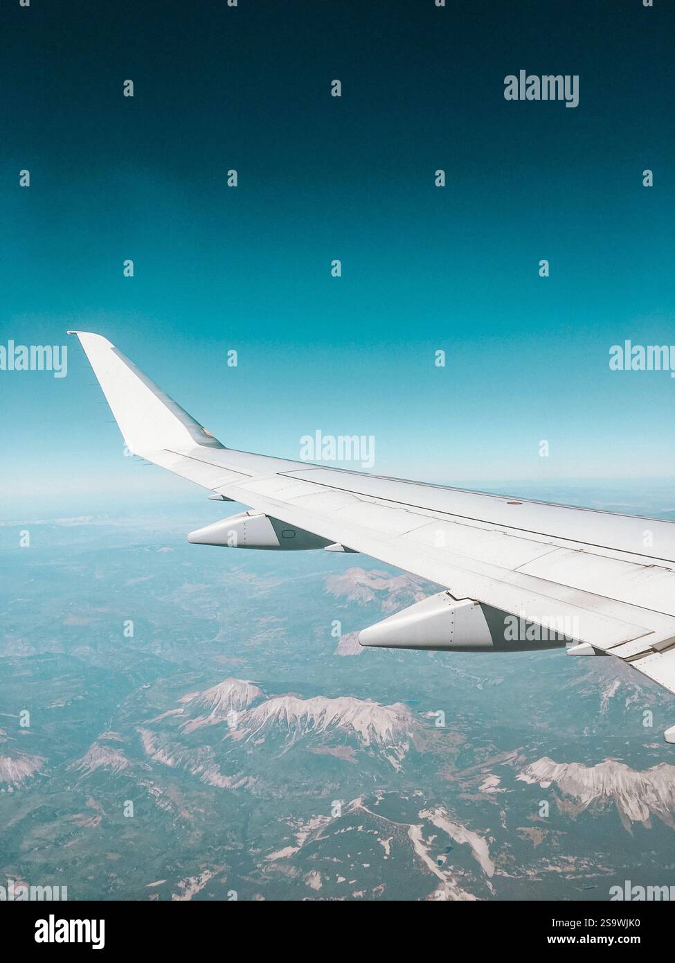 Splendida fotografia di un'ala di un aeroplano che si innalza sul paesaggio montuoso della Grecia, catturando le spettacolari vette e valli sottostanti. Foto Stock