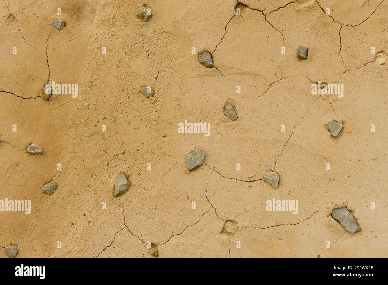 Pareti di fango incrinate con texture in pietre incorporate Foto Stock