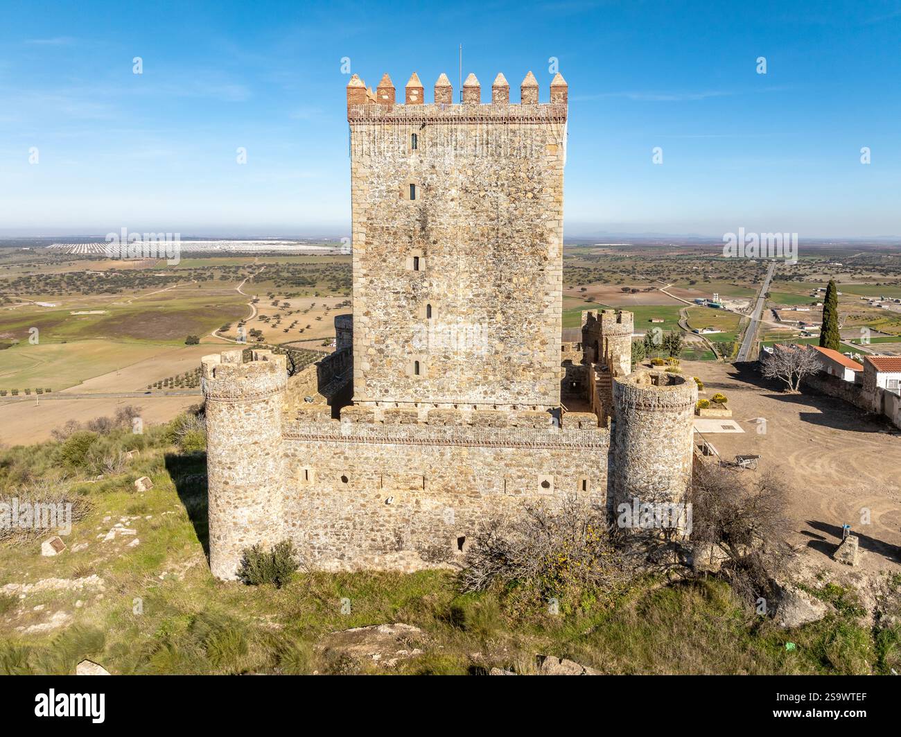 Vista aerea del castello di Nogales in Spagna con torre omaggio, merlature e 4 torri circolari sulla cima di una collina Foto Stock