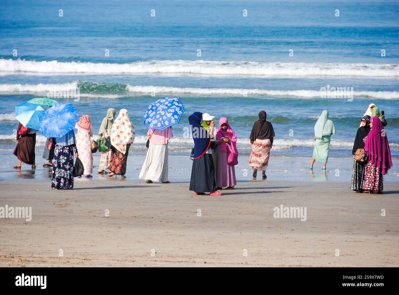 Donne che guardano il mare sulla spiaggia di Kuta, Bali, vestite con abiti tradizionali Foto Stock
