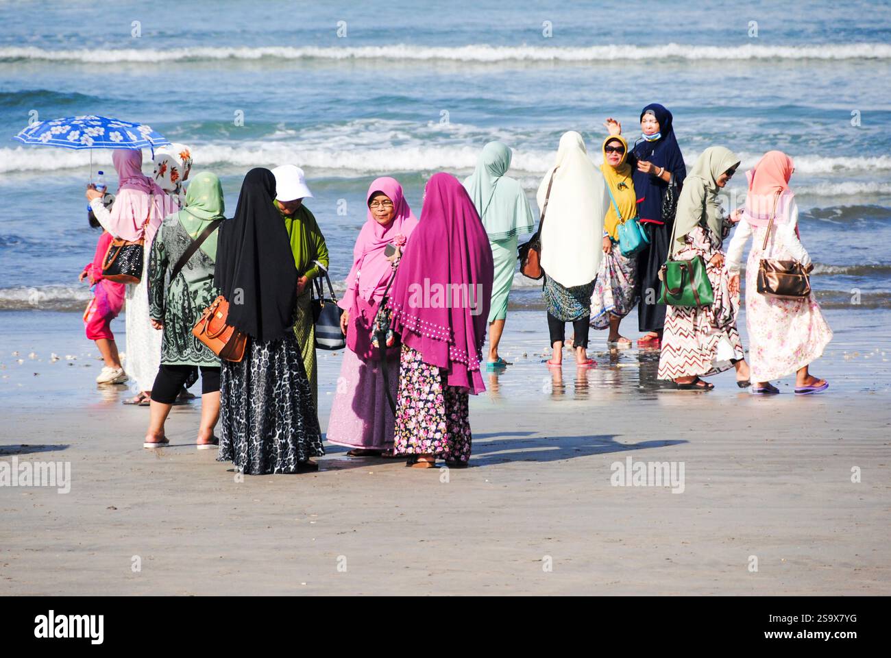 Donne in abbigliamento tradizionale che si godono la spiaggia e scattano foto a Kuta Beach, Bali Foto Stock