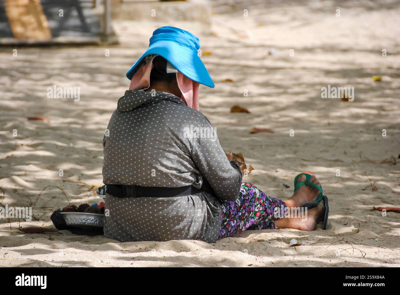 Donna balinese che riposa tranquillamente sulla spiaggia, godendo dell'atmosfera tranquilla Foto Stock