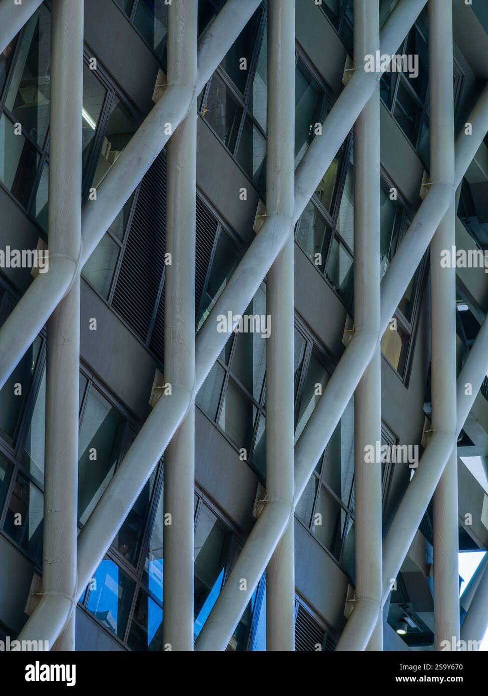 Dettagli ravvicinati della facciata geometrica di un edificio di Hong Kong. L'intricato telaio in acciaio e il motivo della finestra creano una texture visiva sorprendente. Foto Stock