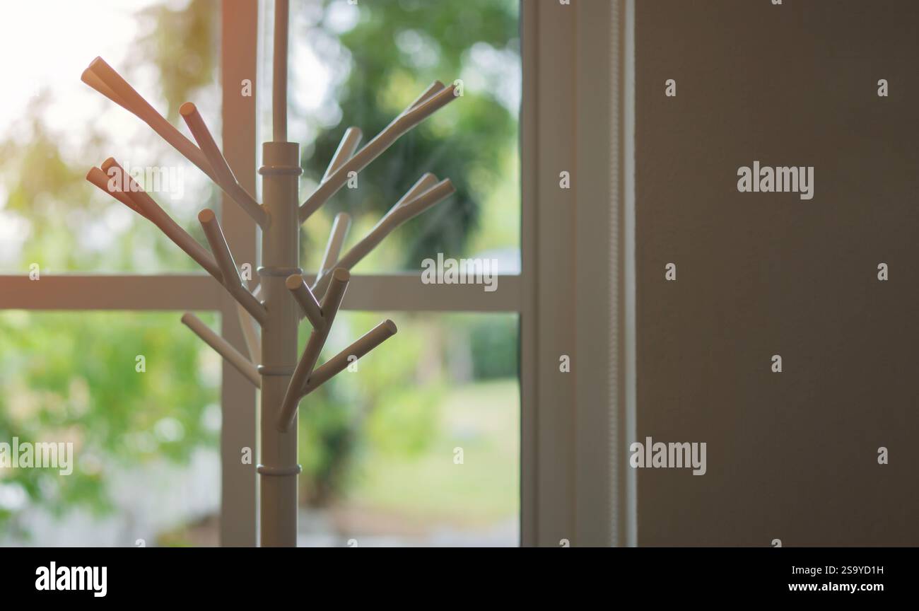 Portabicchieri in tessuto bianco vuoto con sfondo beige accanto alla finestra di casa. Foto Stock