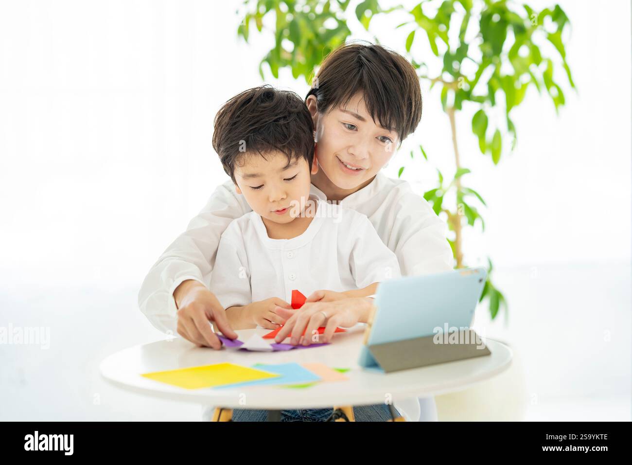 Genitori e bambini che fanno l'origami mentre guardano un tablet PC Foto Stock