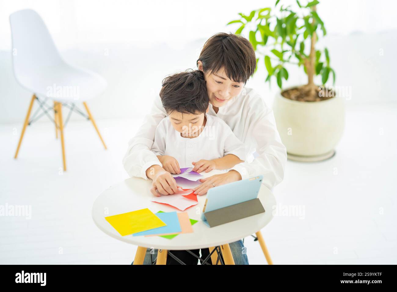 Genitori e bambini che fanno l'origami mentre guardano un tablet PC Foto Stock
