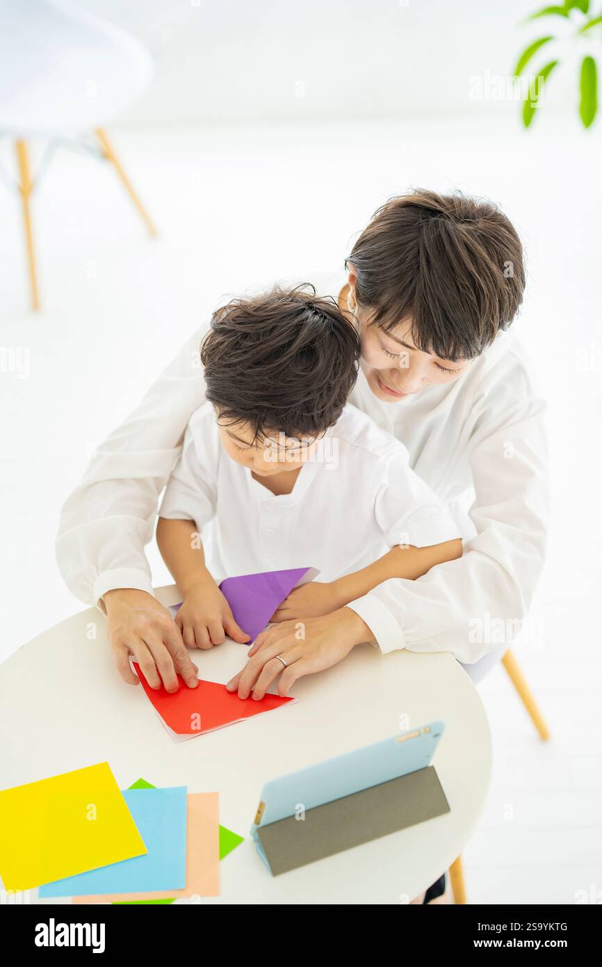 Genitori e bambini che fanno l'origami mentre guardano un tablet PC Foto Stock