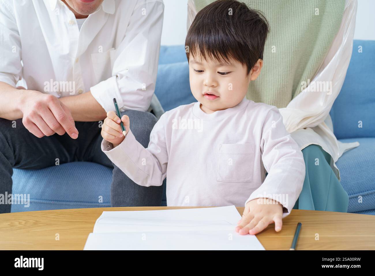 Ragazzo che disegna con matita e genitori che guardano Foto Stock