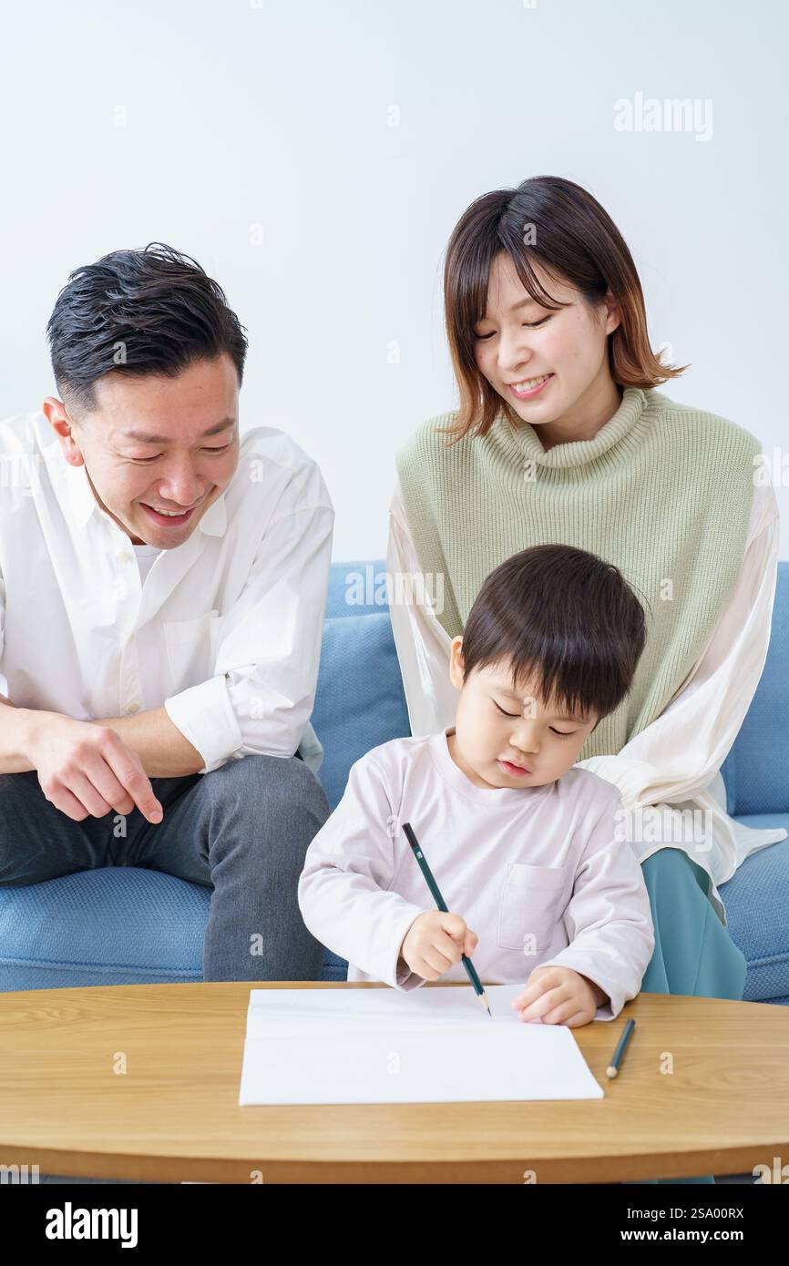 Ragazzo che disegna con matita e genitori che guardano Foto Stock