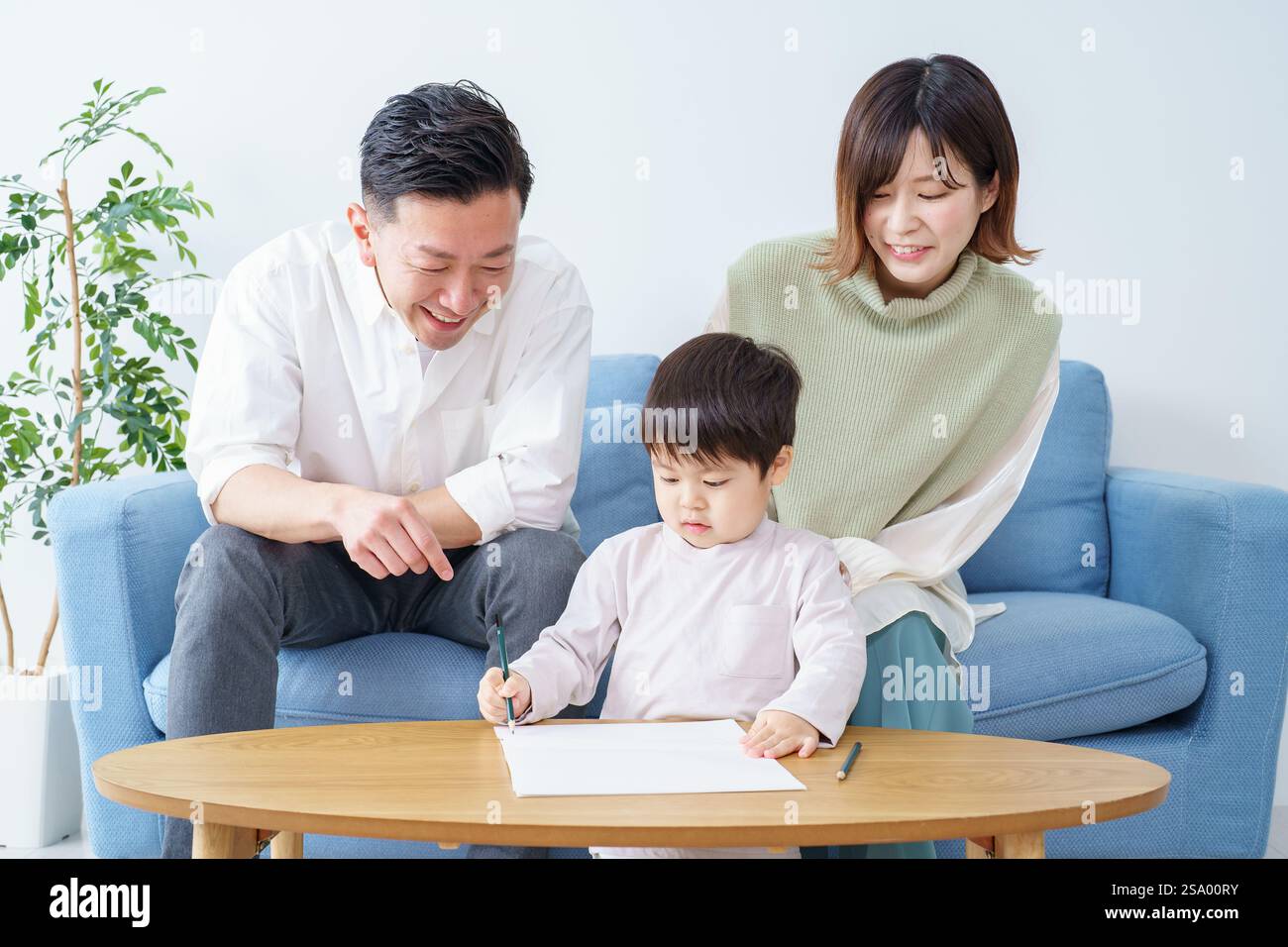 Ragazzo che disegna con matita e genitori che guardano Foto Stock
