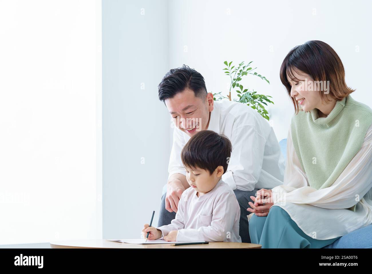 Ragazzo che disegna con matita e genitori che guardano Foto Stock