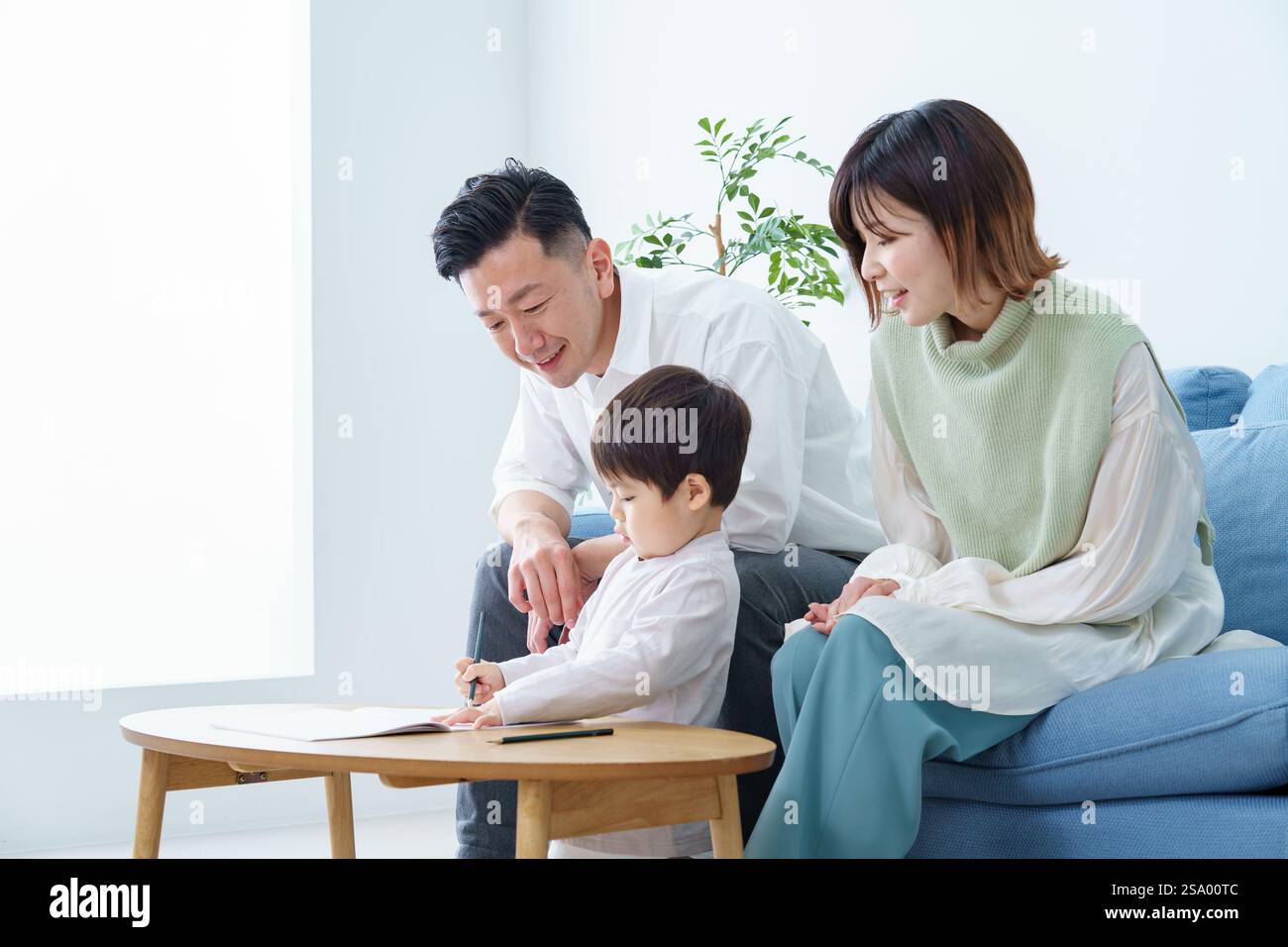 Ragazzo che disegna con matita e genitori che guardano Foto Stock