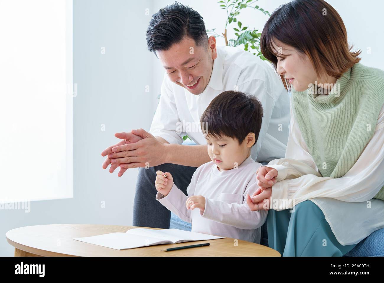 Ragazzo che disegna con matita e genitori che guardano Foto Stock