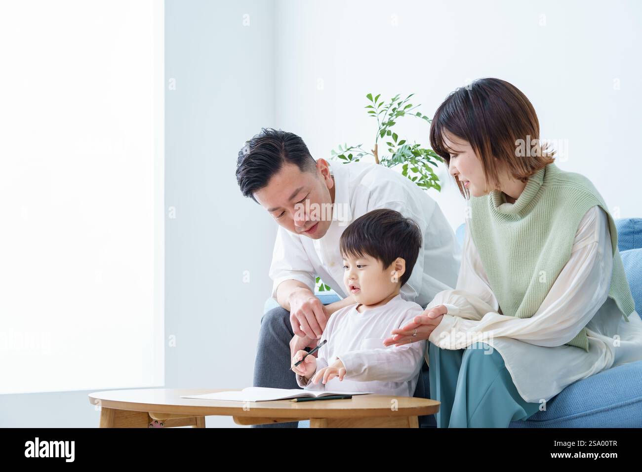 Ragazzo che disegna con matita e genitori che guardano Foto Stock