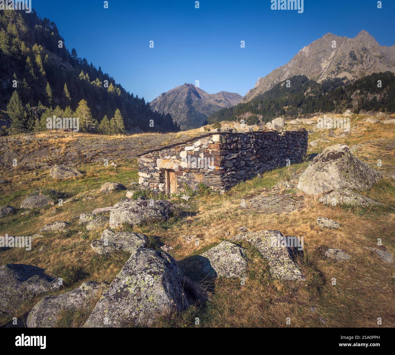 Pietre serene incastonate tra massi, incorniciate da maestose montagne nei Pirenei spagnoli. Foto Stock