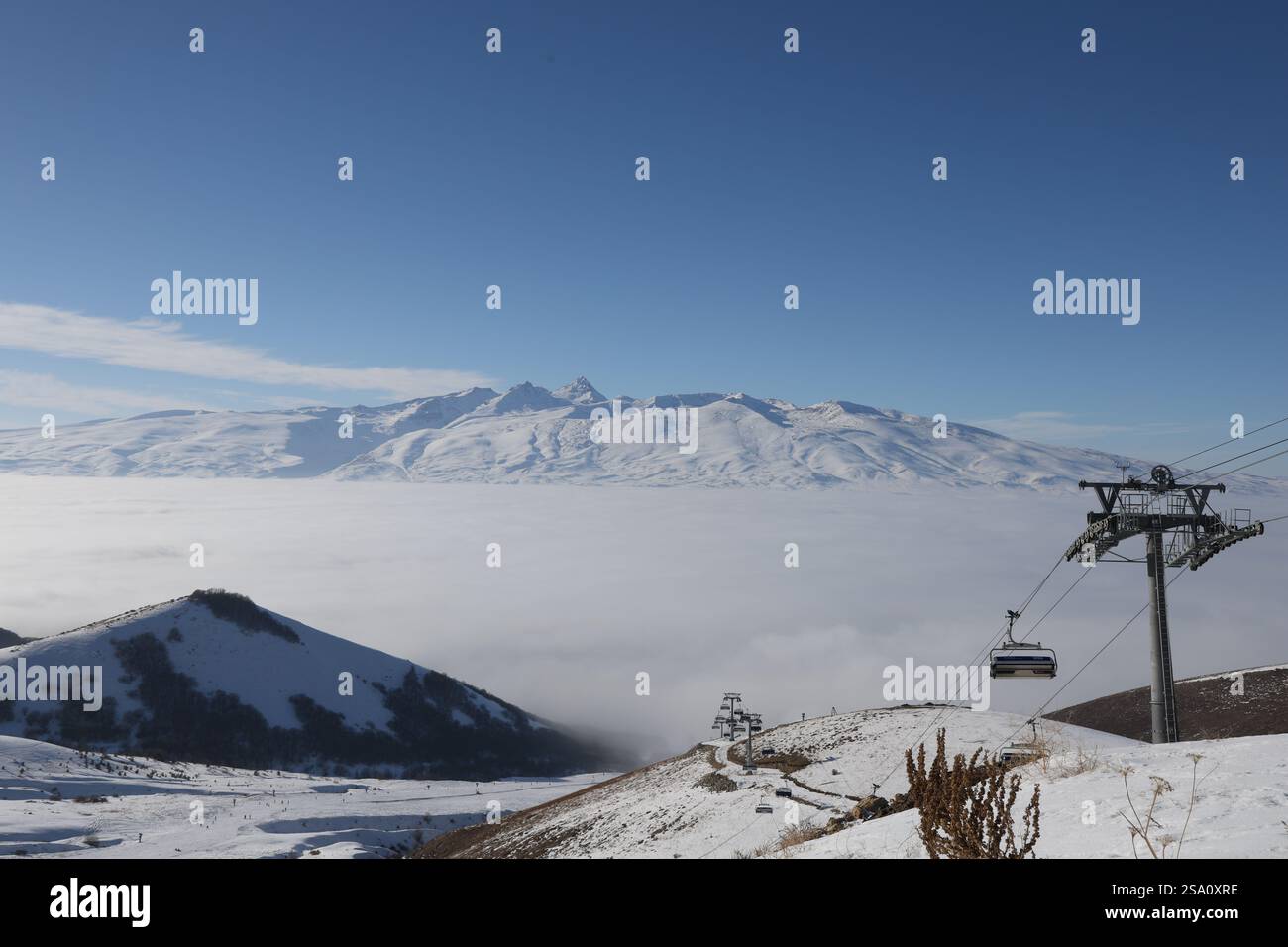 Una splendida vista del monte Aragats a MyLer, Armenia, con uno skilift e una coperta di nuvole che coprono la valle sottostante in una limpida giornata invernale Foto Stock