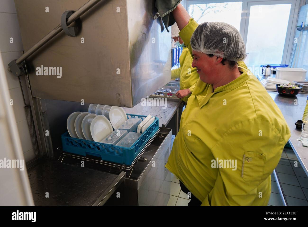 Lavoratori disabili che preparano pasti per gli utenti e le autorità di vigilanza dell' ESAT . Immergiti nella lavastoviglie locale. Foto Stock