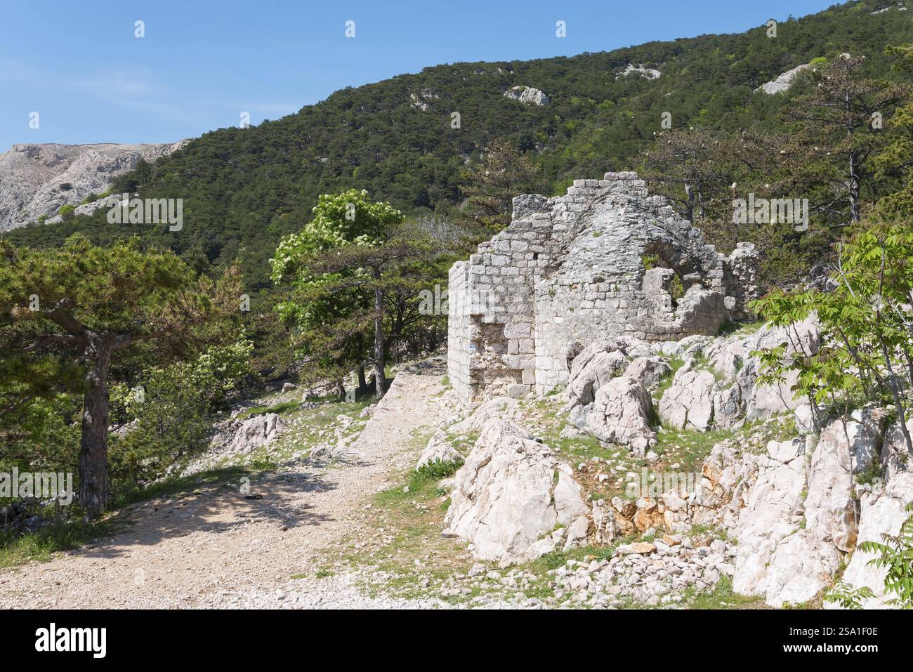 Il muro di pietra abbandonato rimane in un paesaggio montagnoso con un sentiero alla luce del sole, la Chiesa dello Spirito Santo, BaTka, Baska, l'isola di Krk, K. Foto Stock