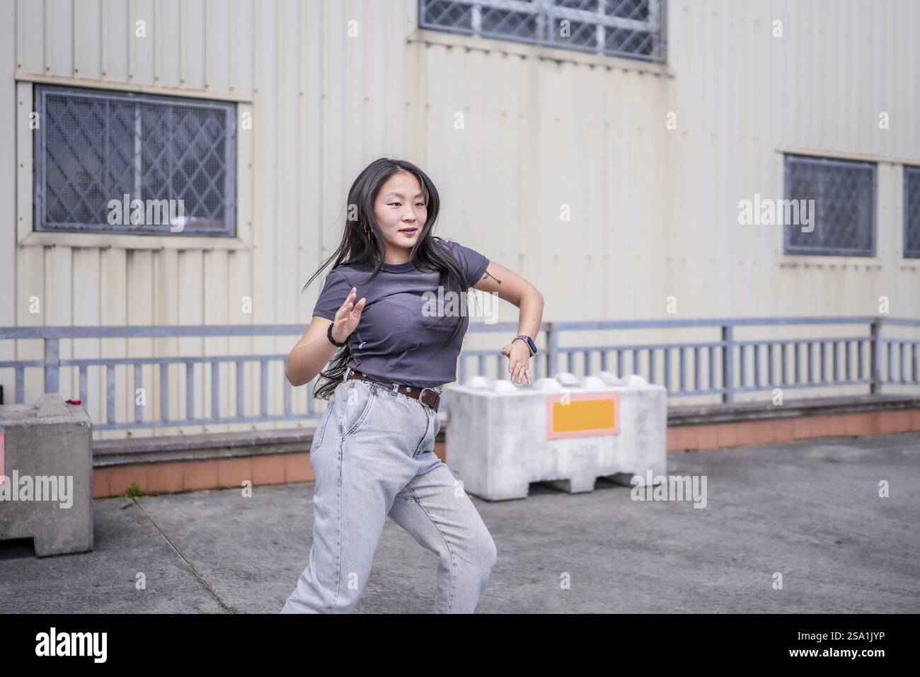 Giovane donna asiatica che gestiva imitando un robot che danzava una danza k-pop urbana in città Foto Stock