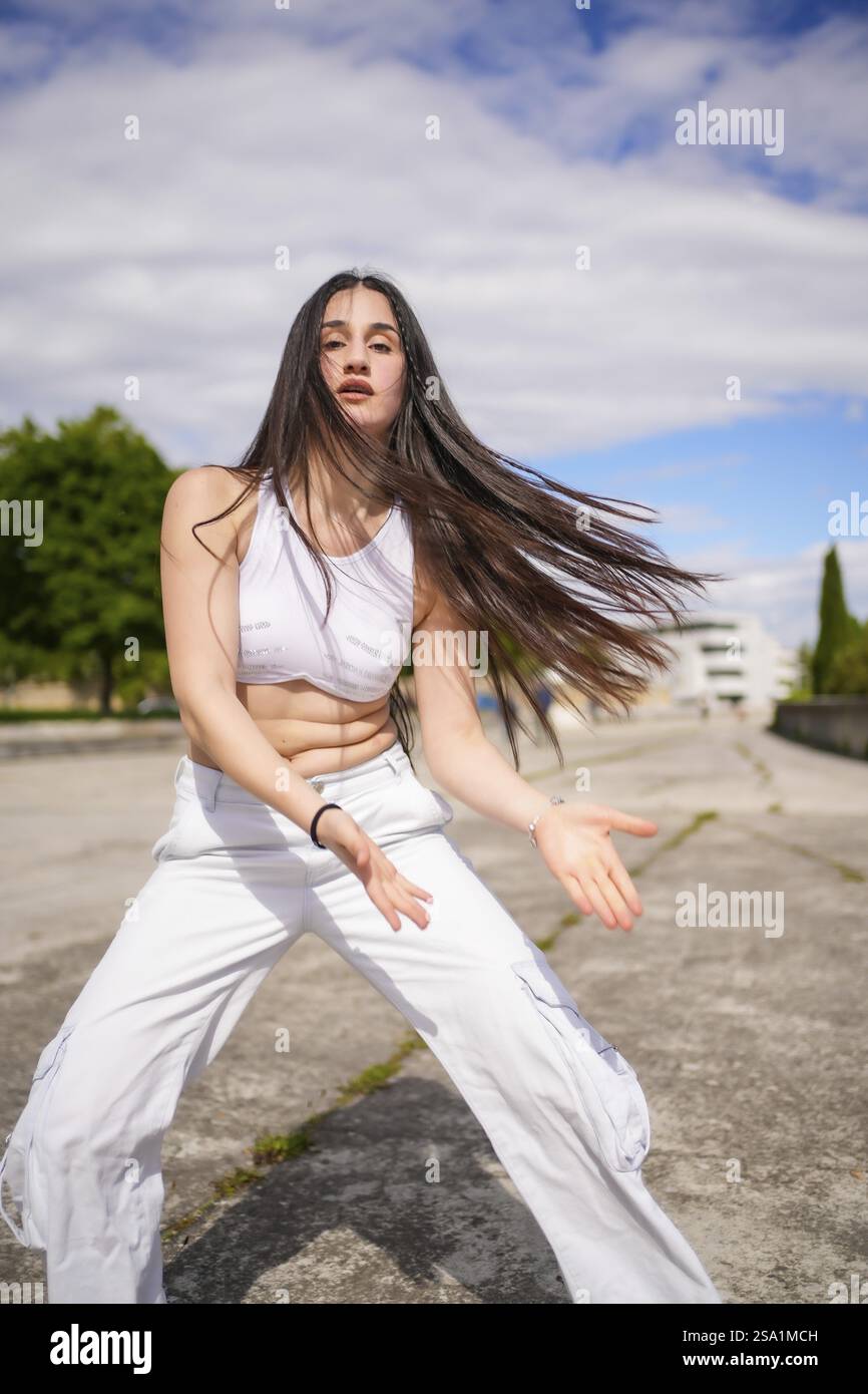 Foto verticale di una giovane donna di bellezza caucasica che danza energicamente freestyle in un parco urbano Foto Stock