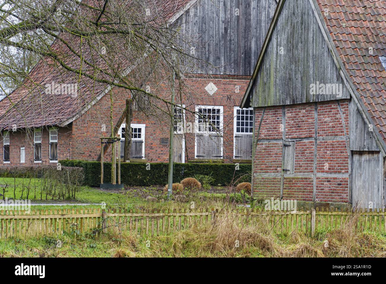 Casa colonica in mattoni e graticci unica circondata da terreni ricoperti di arbusti e recinzioni, vreden, muensterland, renania settentrionale-vestfalia, germania Foto Stock