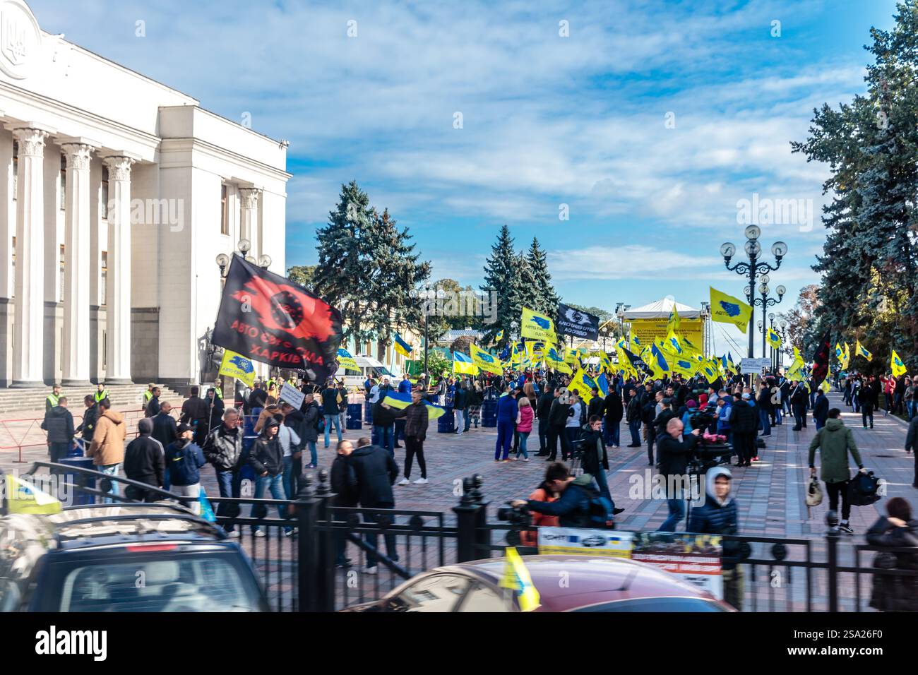 Una grande folla di persone sta protestando di fronte a un edificio. Ci sono molte persone che hanno segni e bandiere, tra cui una che dice "Stop the War". Foto Stock