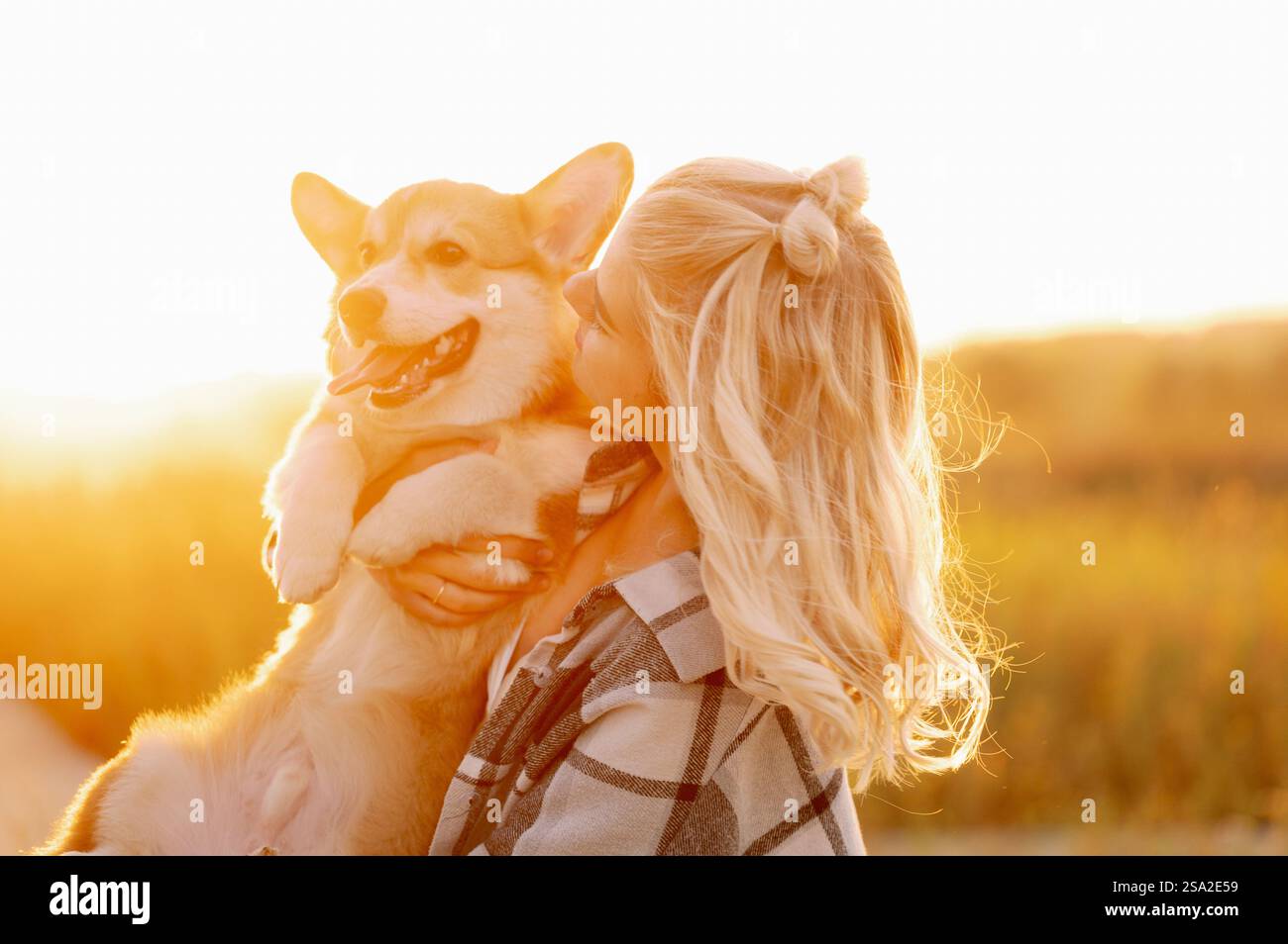 Una donna tiene un bulldog francese tra le braccia, bacia il cane, lo guarda amorevolmente al tramonto. Il concetto di amicizia, fiducia, amore, senza figli. Foto Stock