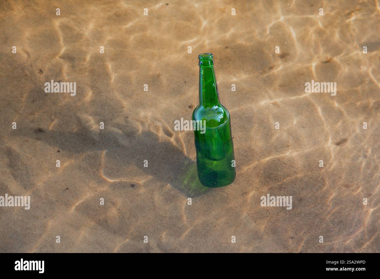 Bottiglia di vetro verde che galleggia in un fiume, collo di bottiglia visto sulla superficie dell'acqua. Concetto di protezione ambientale e controllo dei rifiuti. Foto Stock