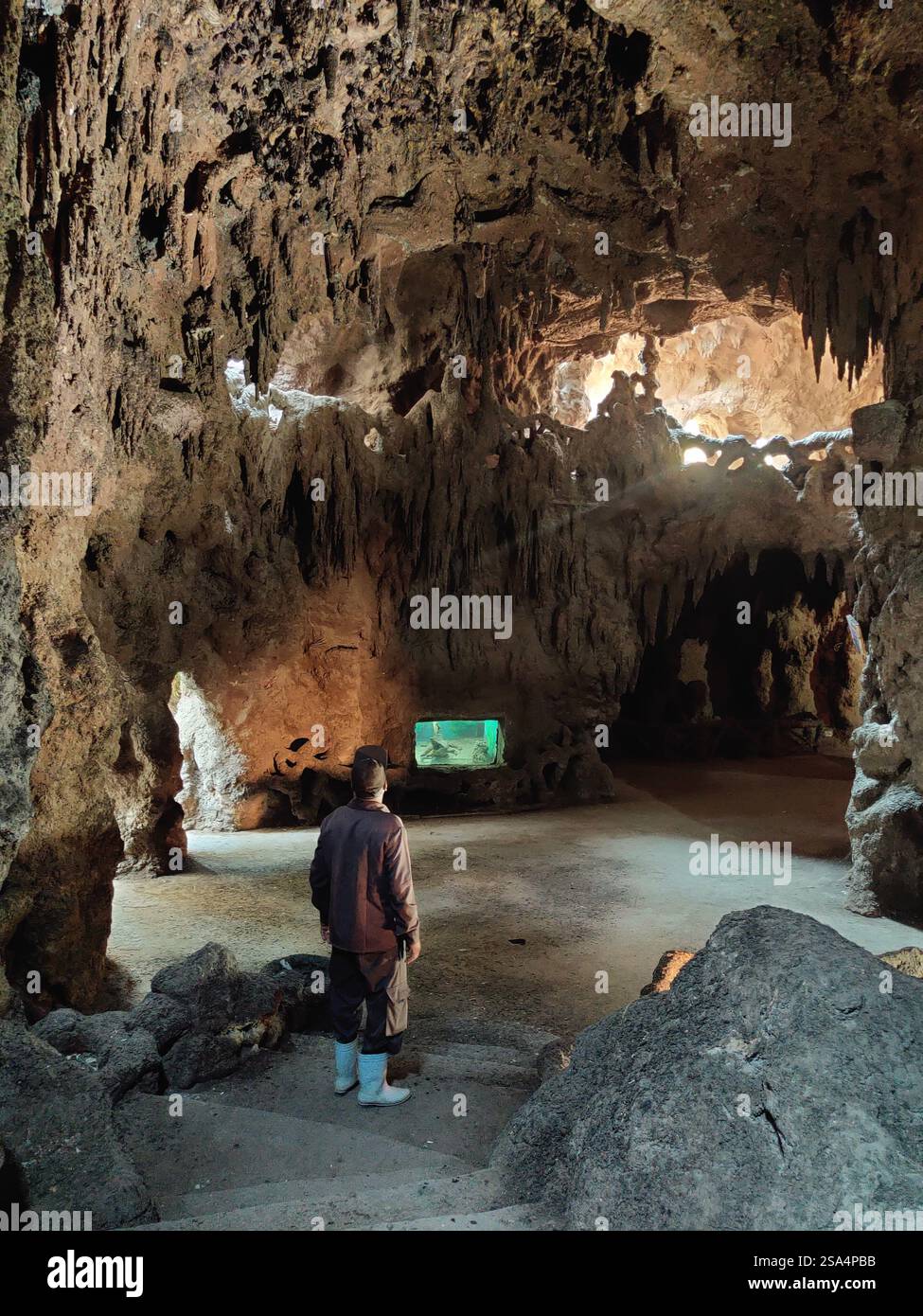 Un lavoratore mi guida attraverso le misteriose grotte del Giardino della Grotta dell'Acquario, dove le formazioni rocciose naturali e la vita acquatica creano una meraviglia nascosta. Foto Stock