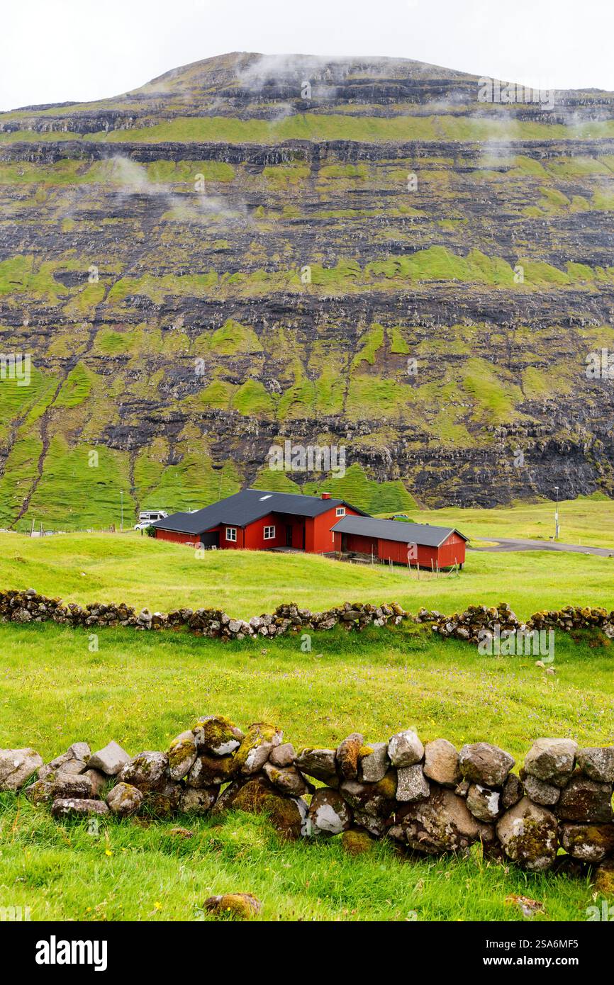 Panorama mozzafiato delle isole Faroe con tradizionale casa rossa con tetto nero Foto Stock