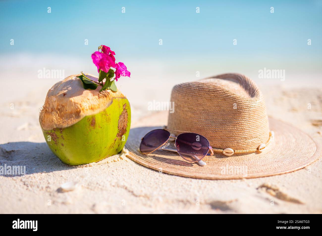 Cappello di paglia, occhiali da sole e noci di cocco su una spiaggia tropicale di sabbia bianca Foto Stock